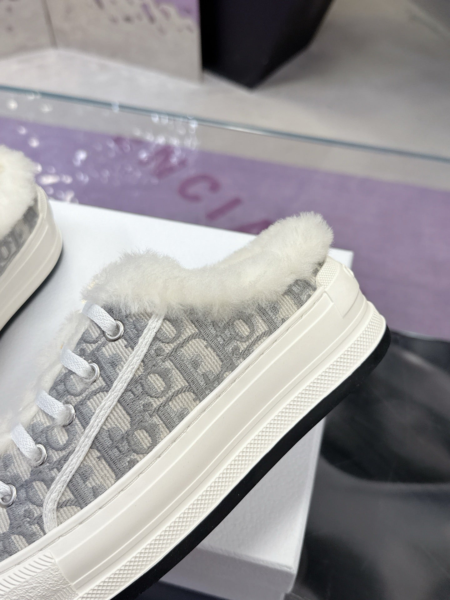 Dior women’s sneaker side view, white sole with gray monogram fabric and plush collar