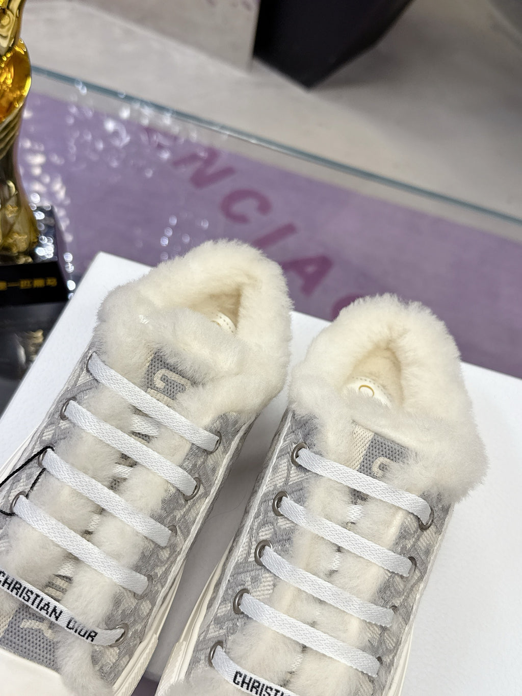 Dior women’s high-top sneakers, front view showing gray logo uppers and white faux-fur lining