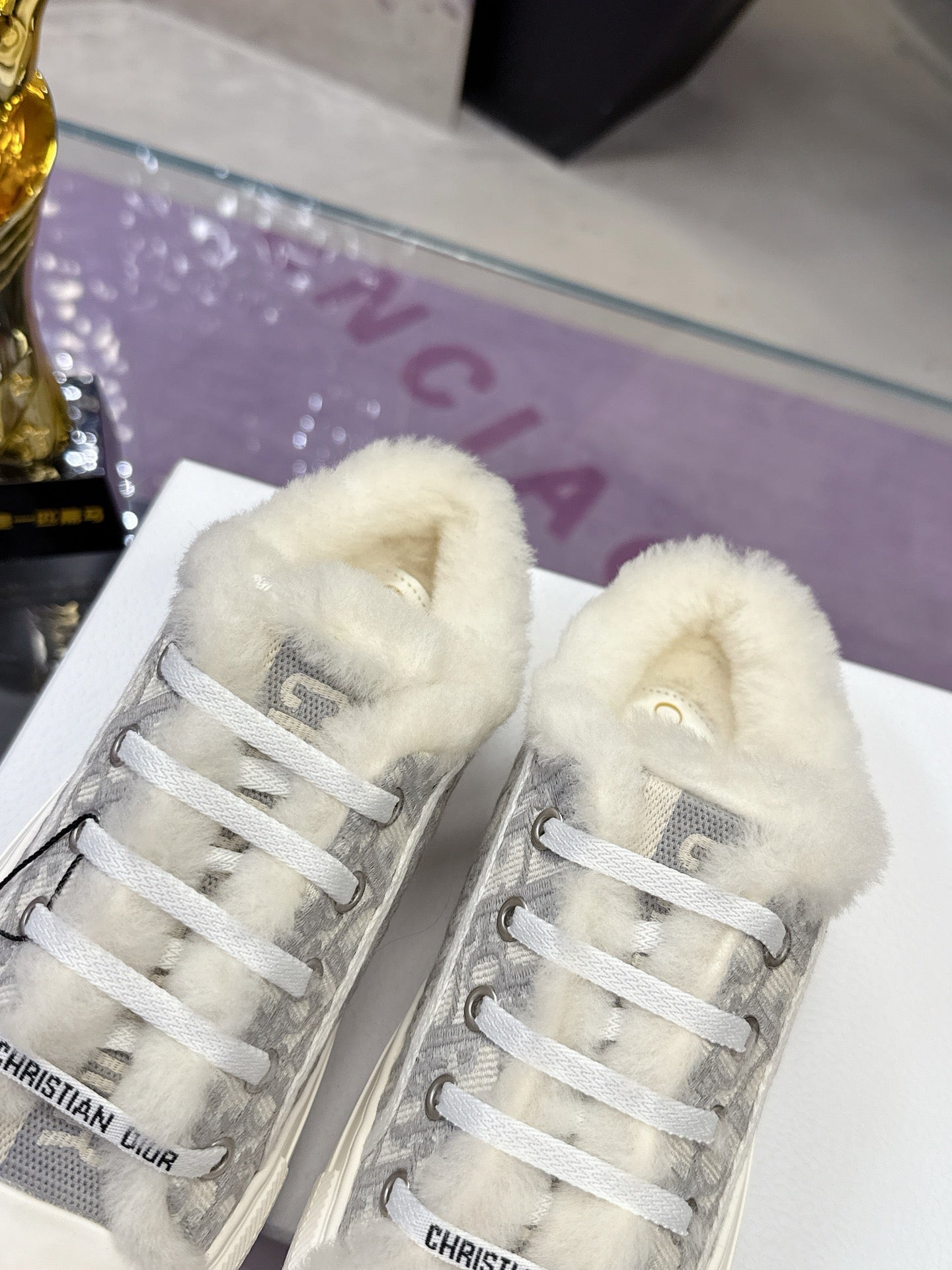 Dior women’s high-top sneakers, front view showing gray logo uppers and white faux-fur lining