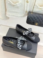 Black leather loafers with white monogram bow and Chanel branding at heel