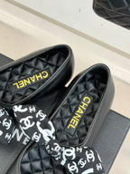 Black loafers with white monogram bow and gold Chanel lettering on insole