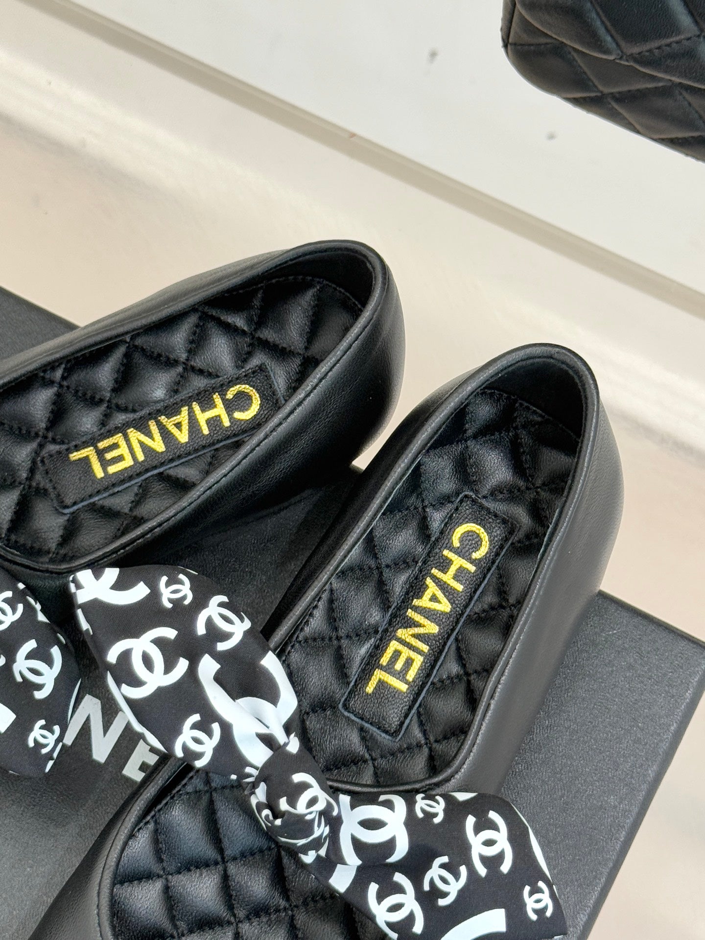 Black loafers with white monogram bow and gold Chanel lettering on insole