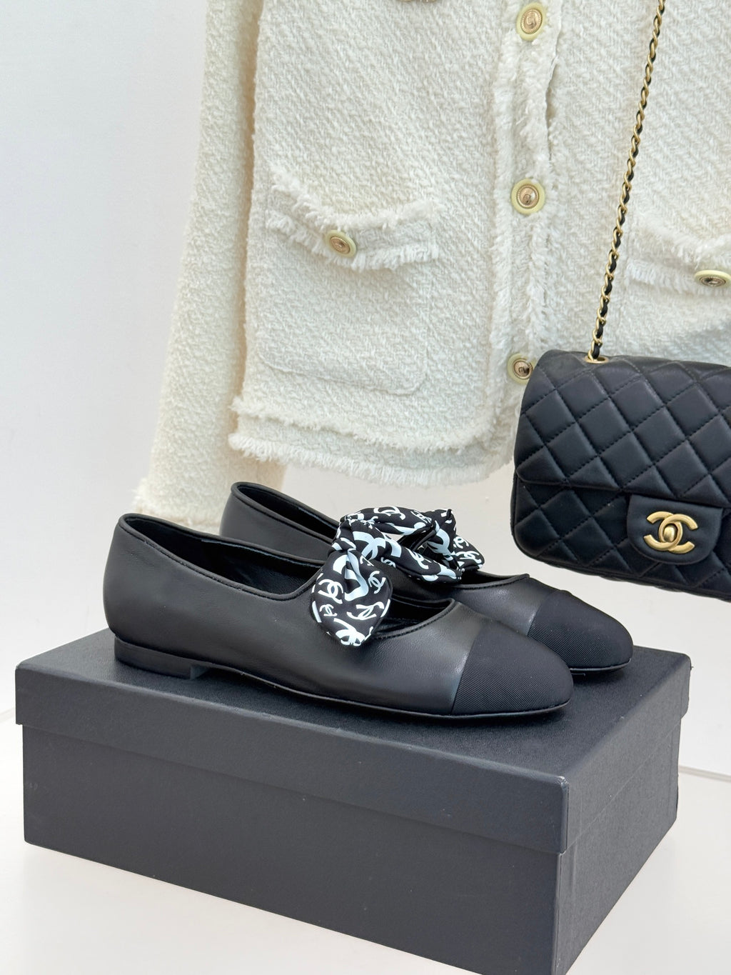 Black leather loafers with white monogram bow, round toe, and Chanel logo detail