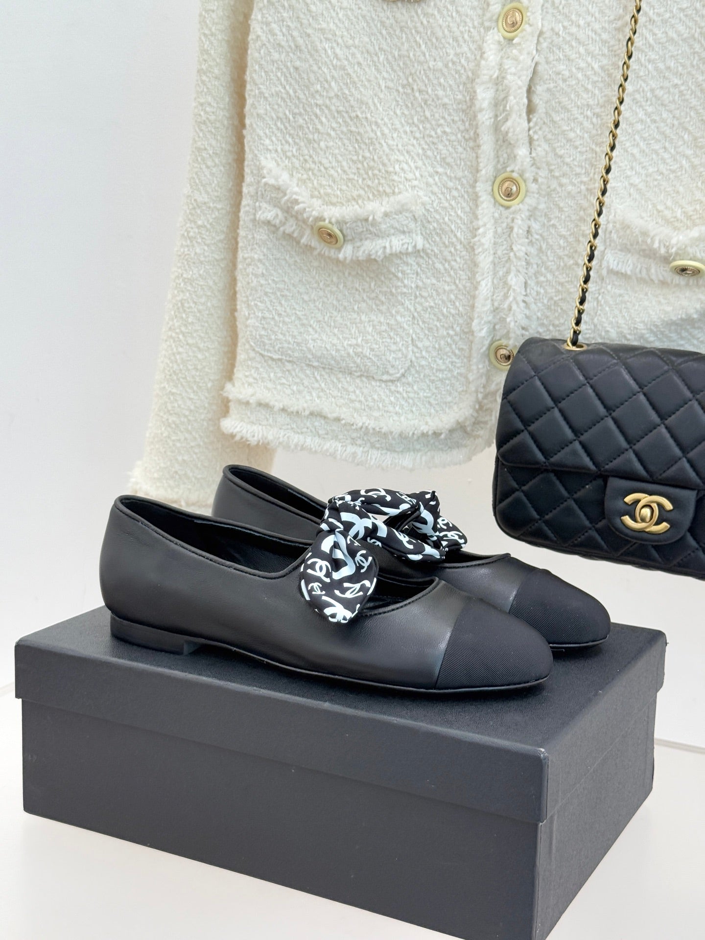 Black leather loafers with white monogram bow, round toe, and Chanel logo detail