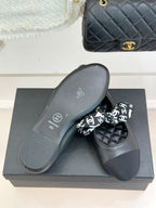 Black loafer pair with white monogram bow and flat sole on display box