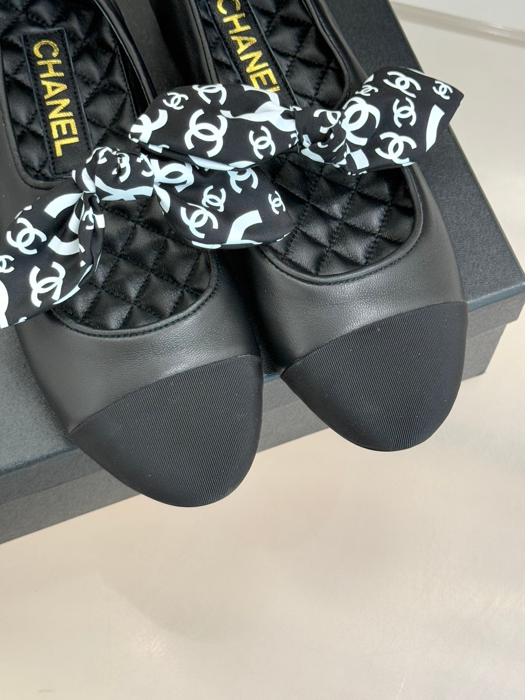 Black loafers with white monogram bow, quilted panels, and Chanel-branded insole