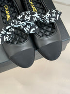 Black loafers with white monogram bow, quilted panels, and Chanel-branded insole