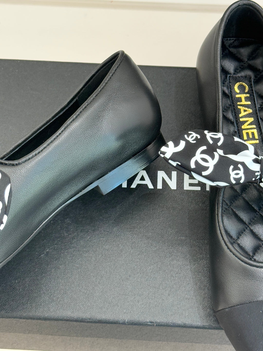 Black leather loafer with white monogram bow and yellow Chanel lettering on insole