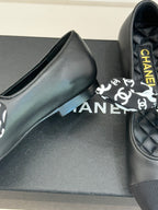 Black leather loafer with white monogram bow and yellow Chanel lettering on insole