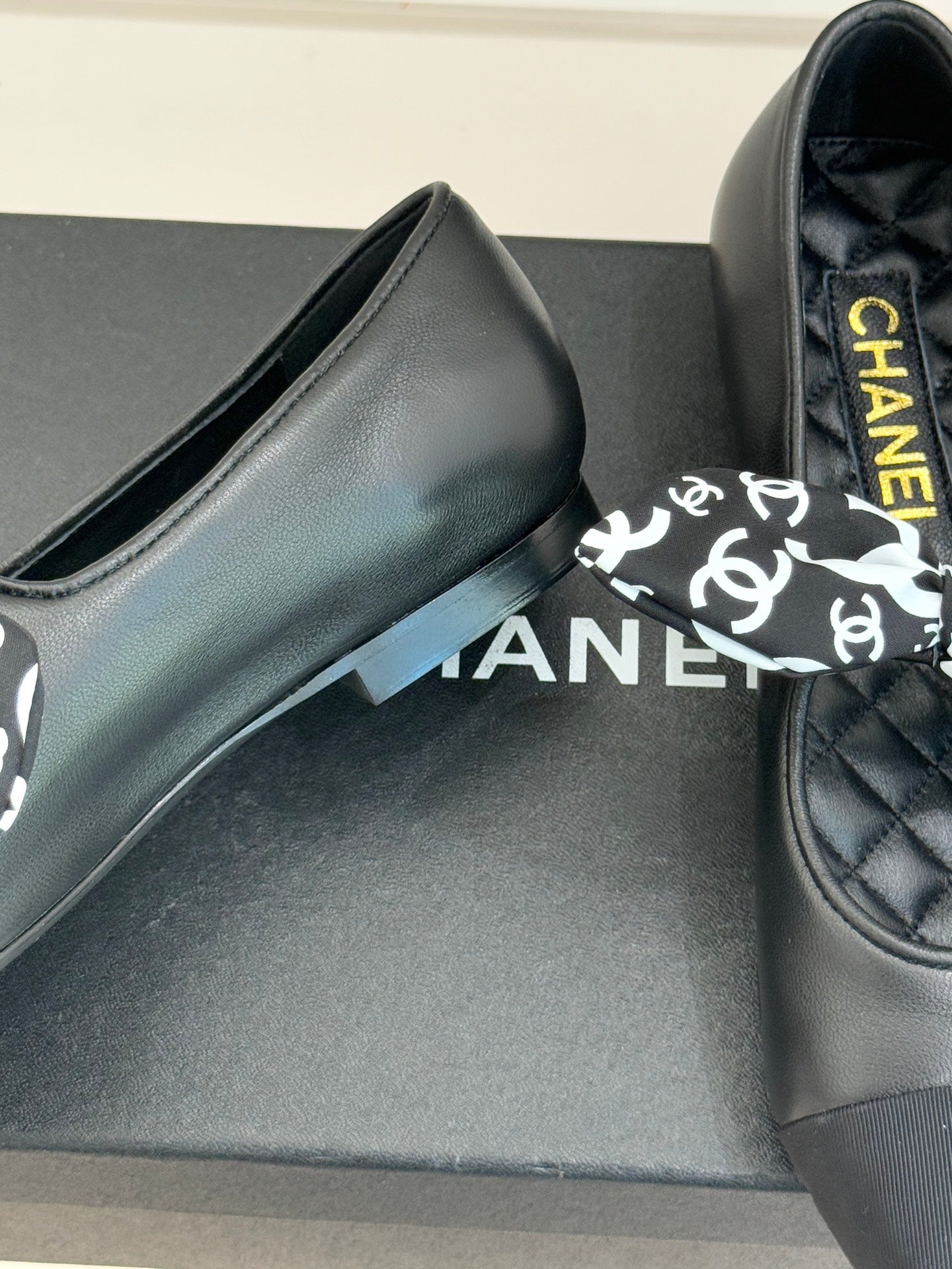 Black leather loafer with white monogram bow and yellow Chanel lettering on insole