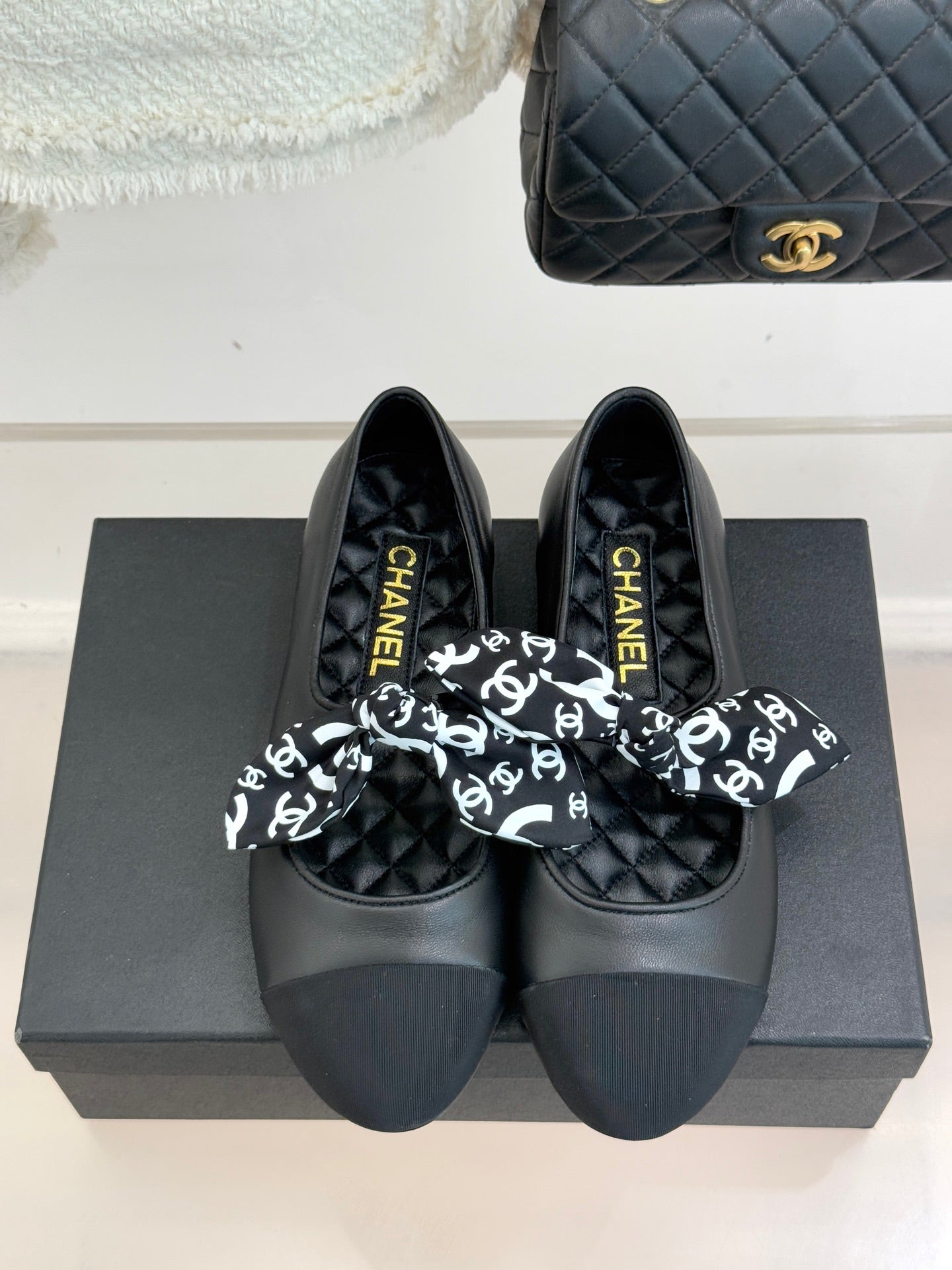 Black slip-on loafers with white monogram bow and gold Chanel logo on insole