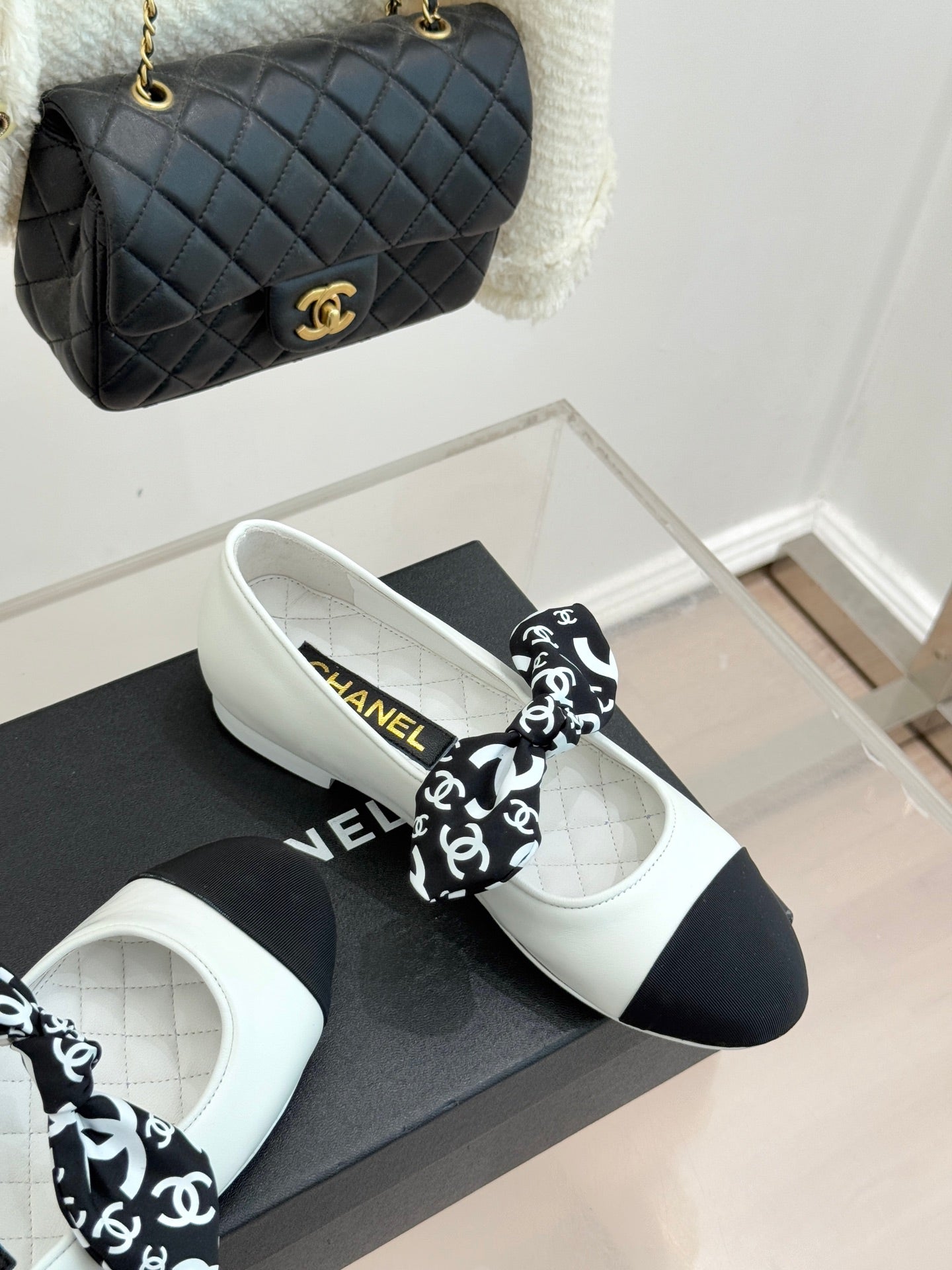 White Chanel ballet flats with black toe and black patterned bow; gold accents.