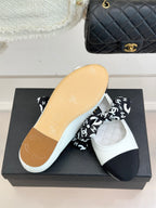 White Chanel ballet flats with black toe; view of light sole on box.