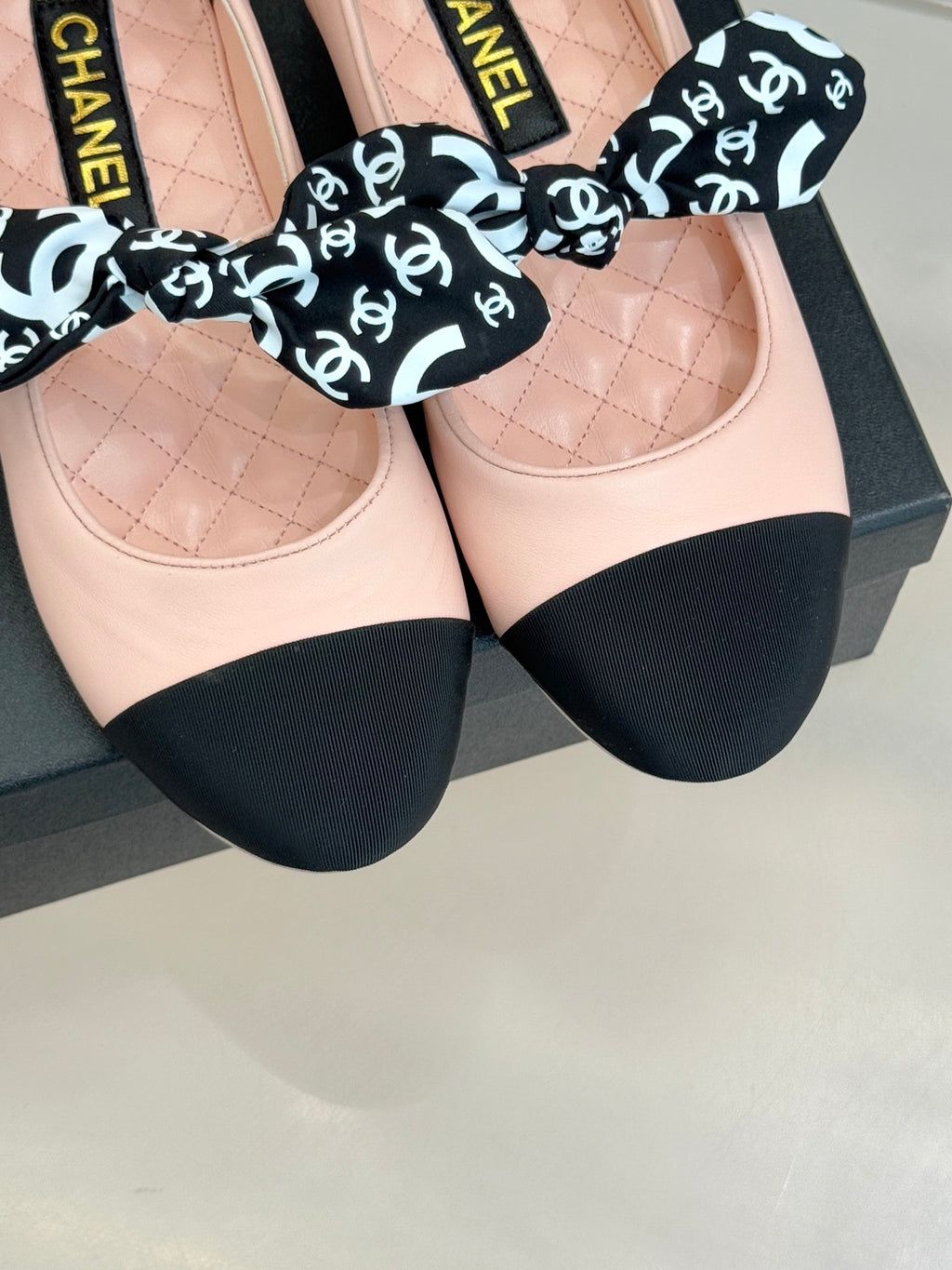 Blush pink ballet flats with black toe panels and Chanel logo bow
