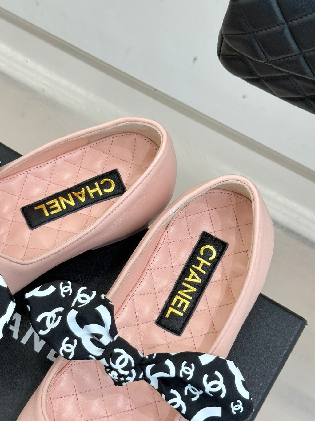 Blush pink ballet flats with Chanel logo tongue label and patterned black bow