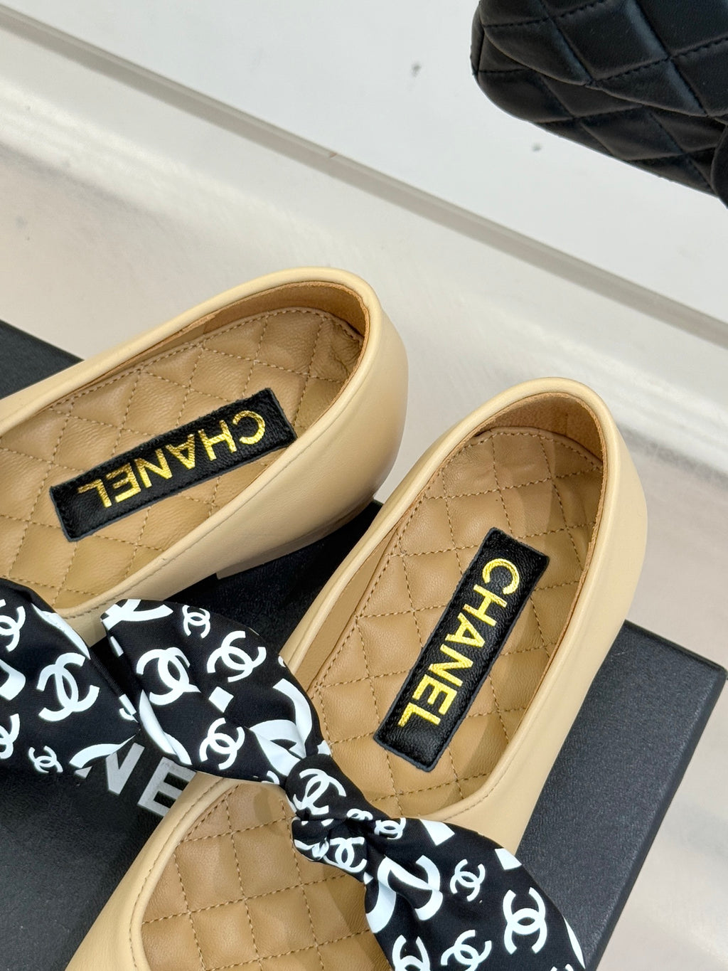 Beige flats with CHANEL label on insole and black logo bow, navy toe cap