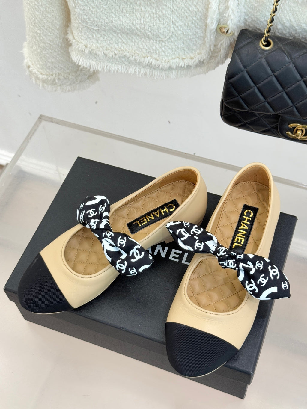 Beige and navy flats on box, black logo bow; insoles show CHANEL lettering