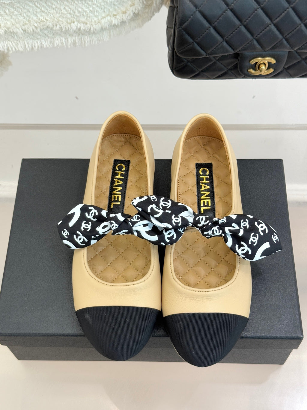 Beige ballet flats with navy toe caps and logo bow; quilted insoles with CHANEL