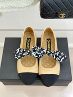 Beige ballet flats with navy toe caps and logo bow; quilted insoles with CHANEL