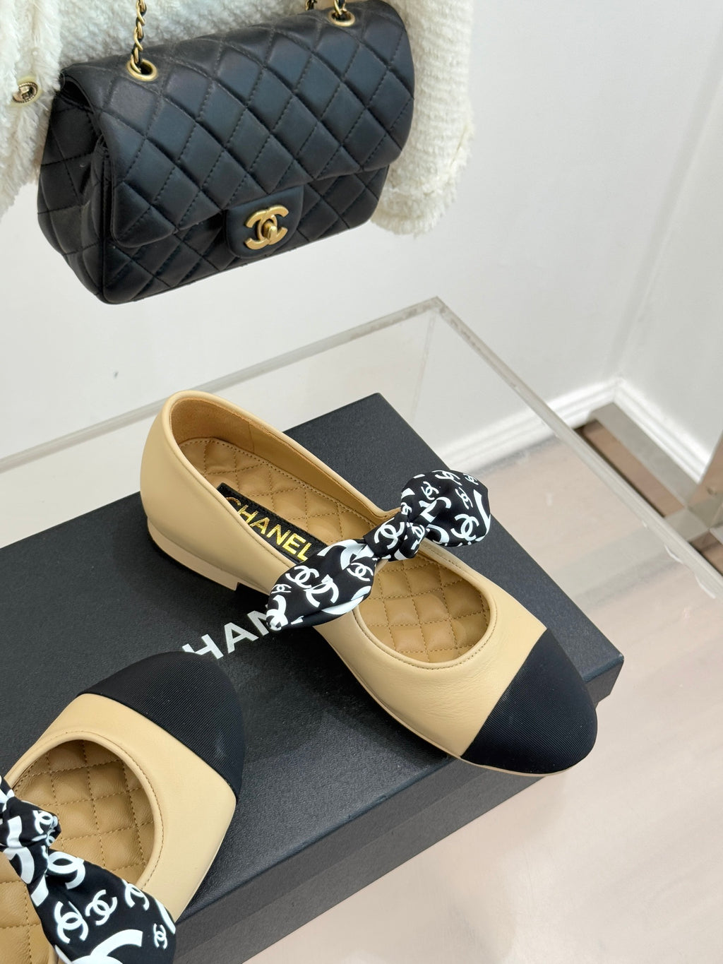 Beige flats with navy toe and black logo bow, leather upper on display box