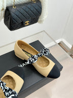 Beige flats with navy toe and black logo bow, leather upper on display box