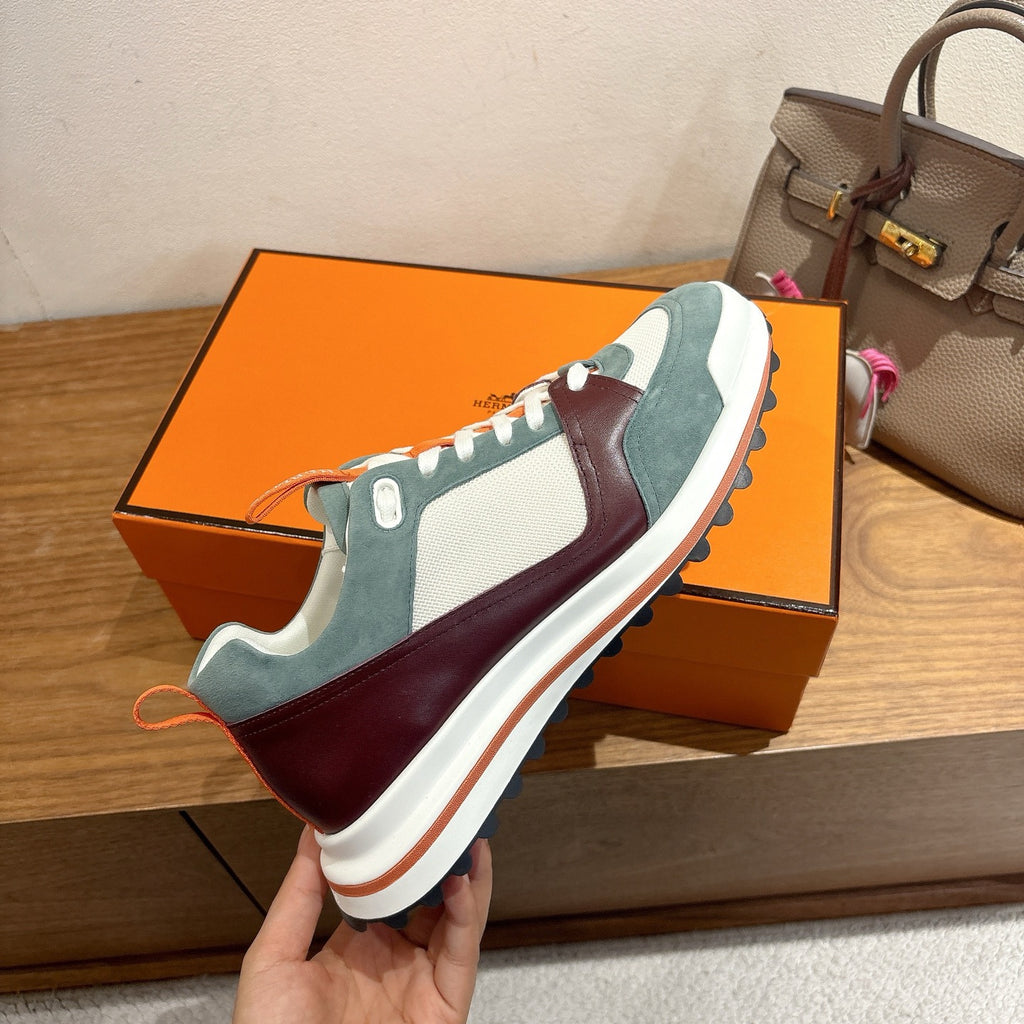 Hermes unisex luxury sneakers held up: teal suede, burgundy panels, white sole