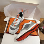 Hermes unisex sneakers, angled view with white upper, gray panels, orange details