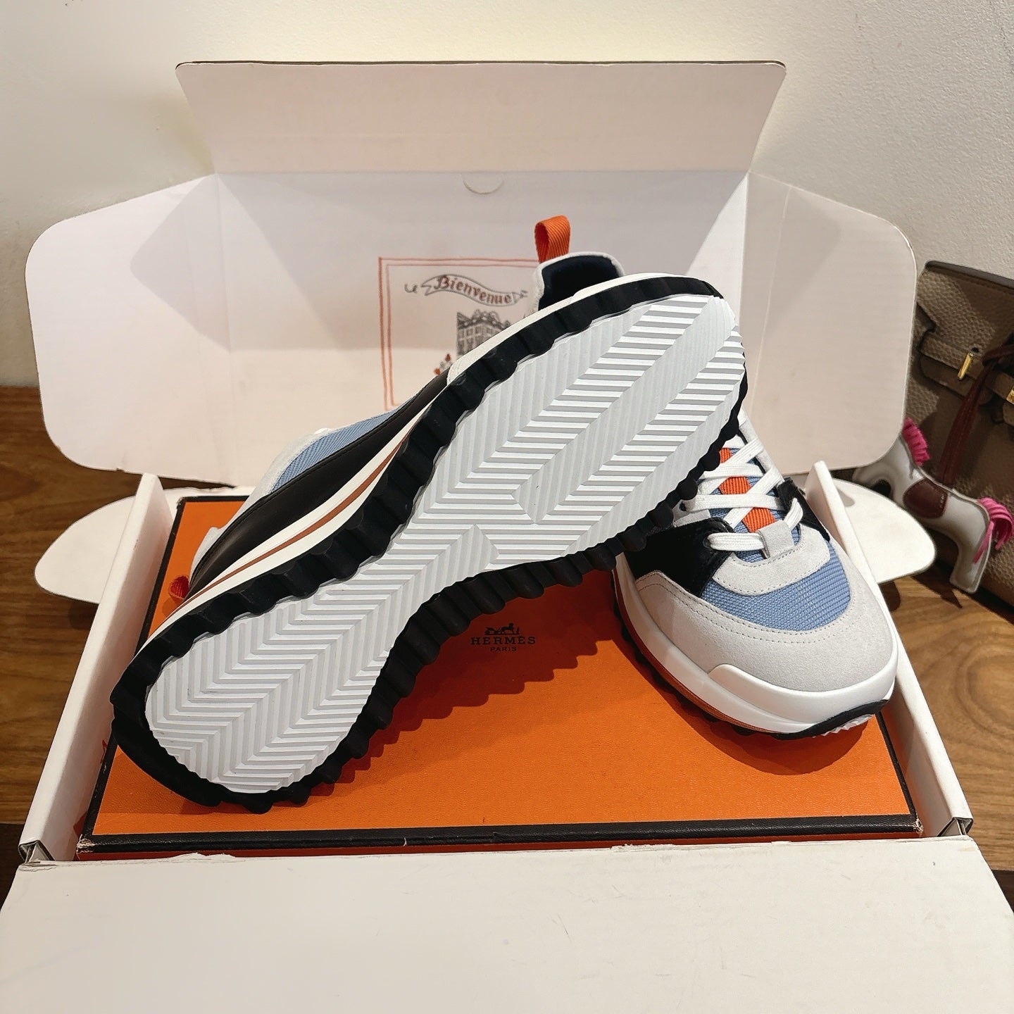Unisex sneaker sole view in box: ridged tread with white, blue, black upper details