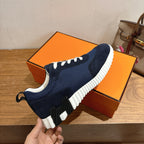 Hermes unisex sneakers held in hand, navy with white laces and thick sole