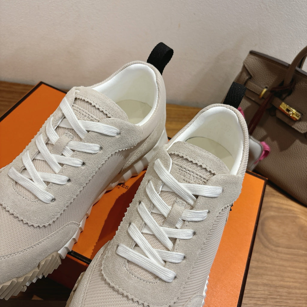 Hermes unisex sneakers close-up, off-white upper with stitched seams and white laces