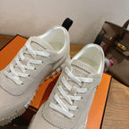 Hermes unisex sneakers close-up, off-white upper with stitched seams and white laces