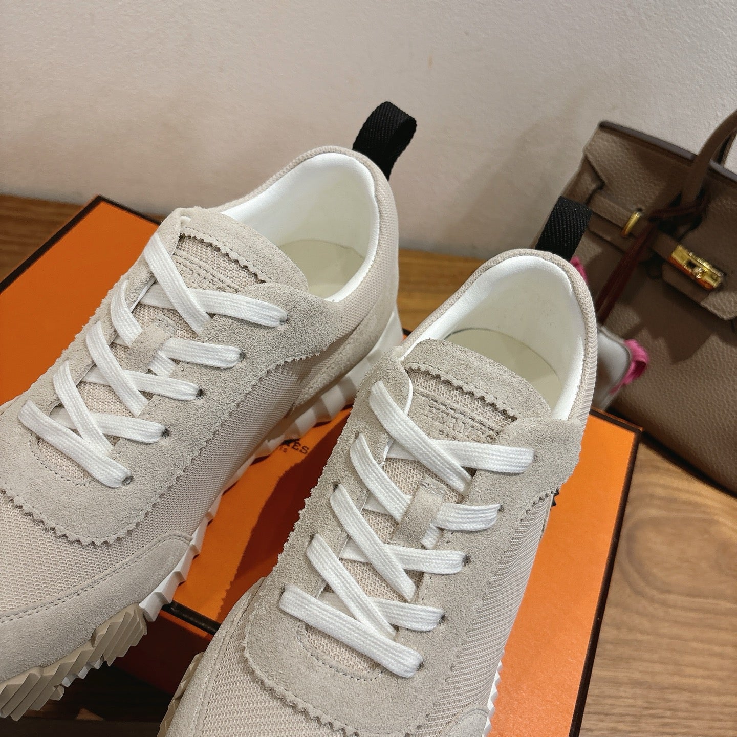 Hermes unisex sneakers close-up, off-white upper with stitched seams and white laces