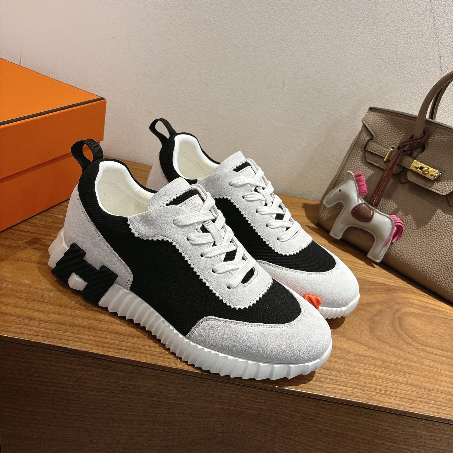 White and black lace-up sneakers with textured rubber sole and orange details
