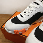 White and black lace-up sneakers with black panel and orange sole detail