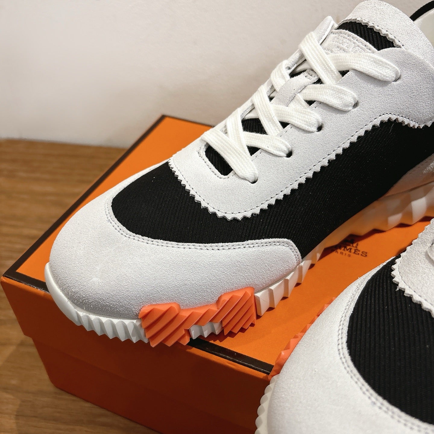 White and black lace-up sneakers with black panel and orange sole detail