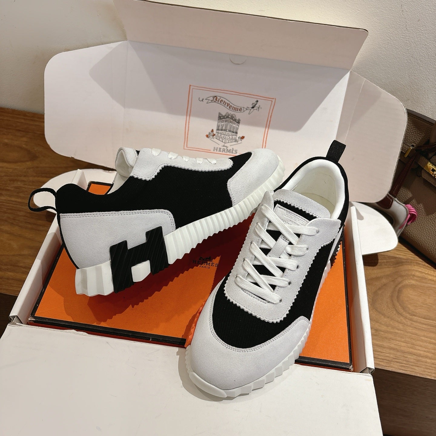 White and black lace-up sneakers with orange sole accents, unisex luxury shoes