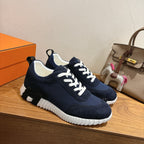 Hermes unisex sneakers in navy with white laces, textured tread sole, side view
