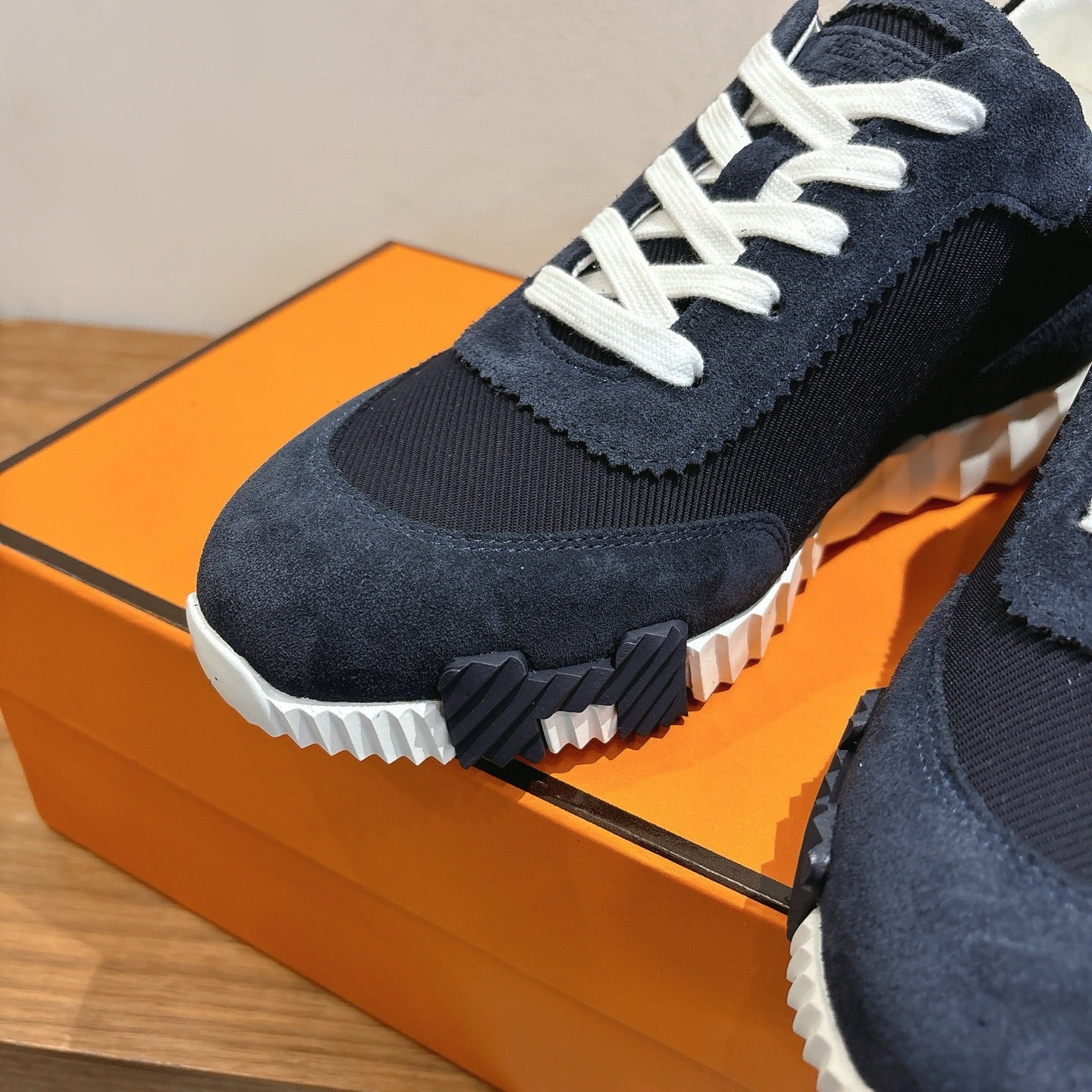 Unisex Hermes sneaker close-up, navy suede upper with white laces and grippy sole