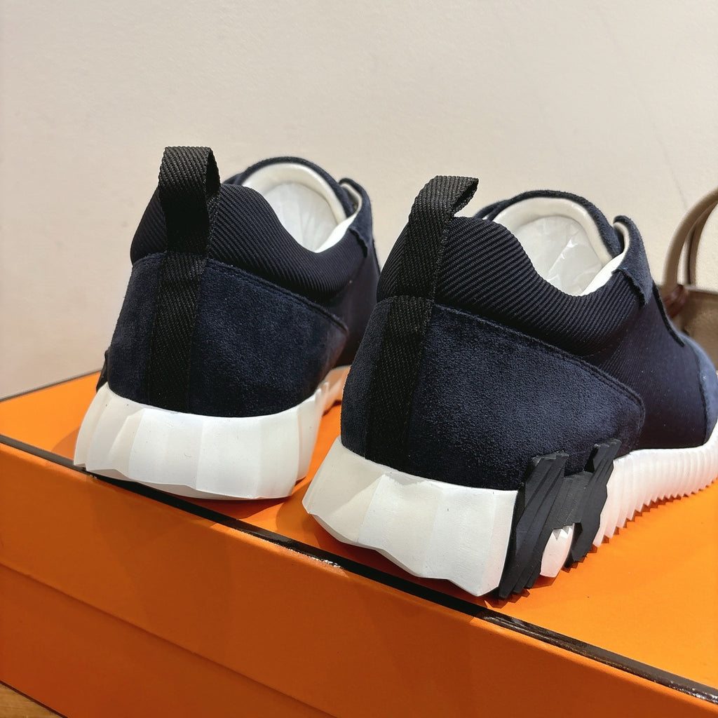 Unisex Hermes sneaker heel view, dark navy suede with white rubber sole and heel tab