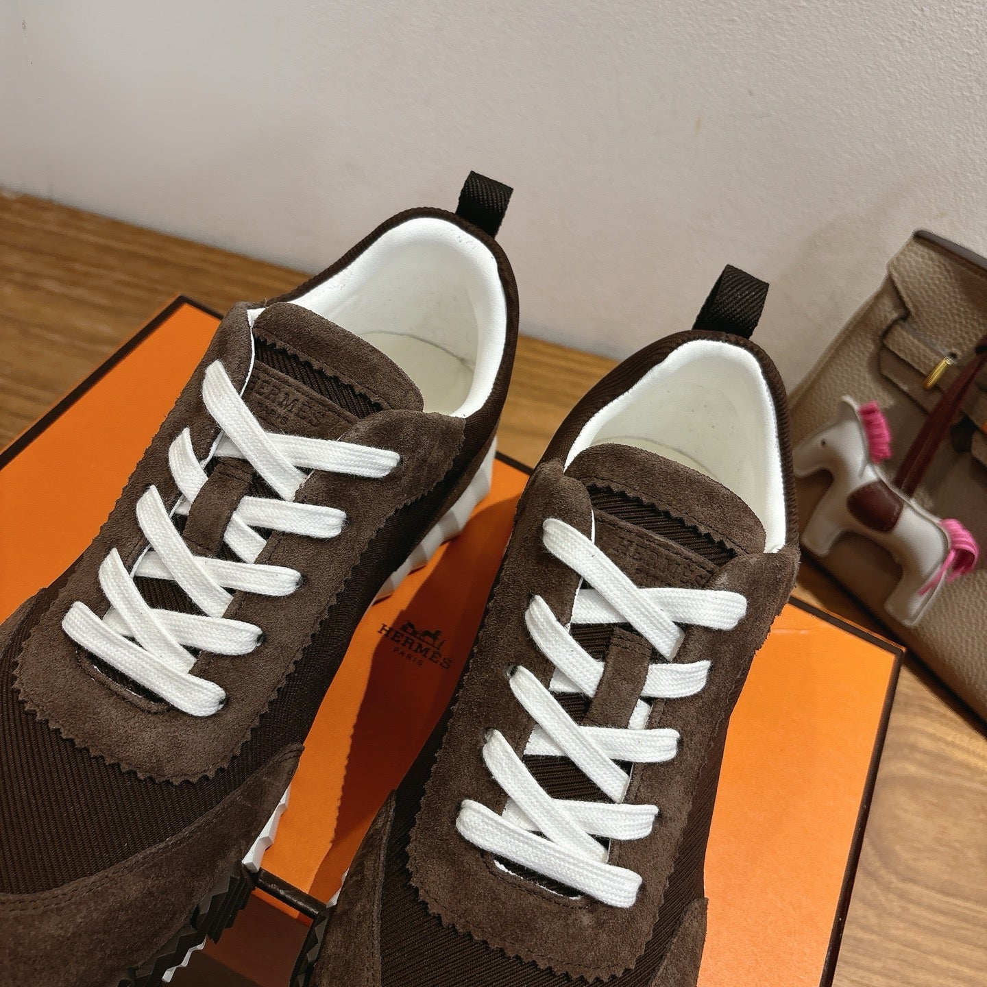 Hermes unisex sneakers close-up, dark brown suede with white laces and ribbed side