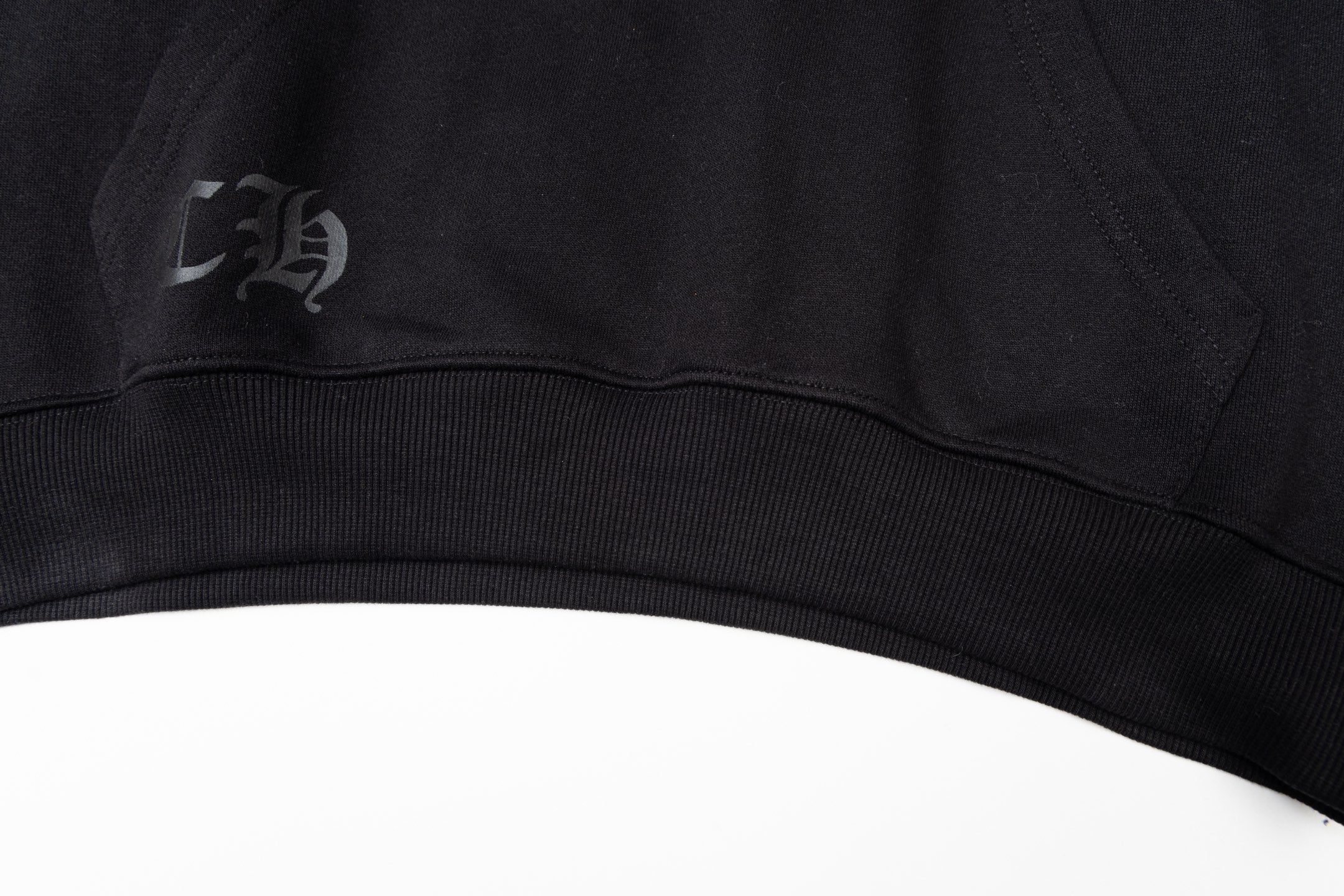 Black long-sleeve hoodie ribbed hem with small stitched logo patch