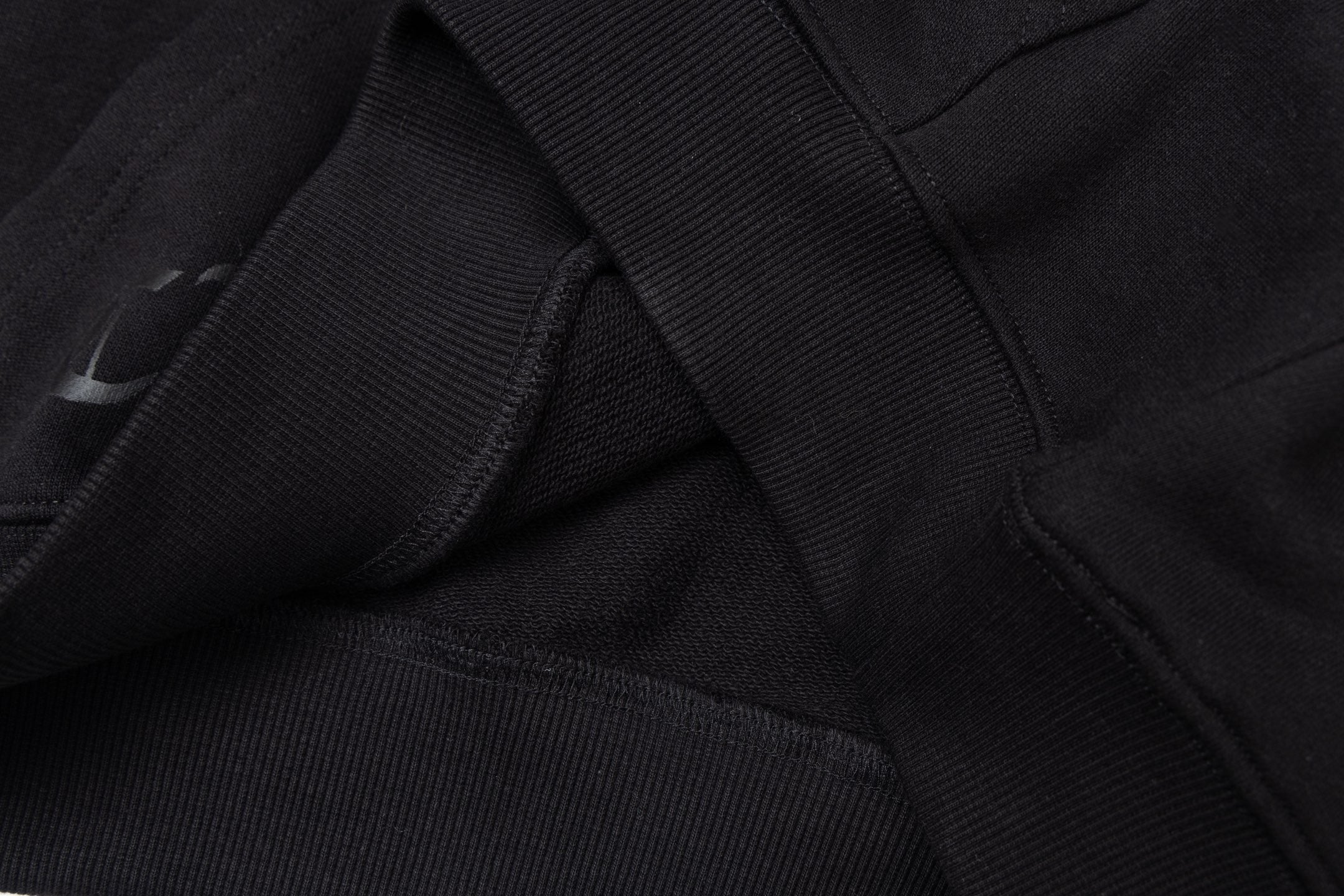 Black hoodie fabric detail with stitched seams and folded panel