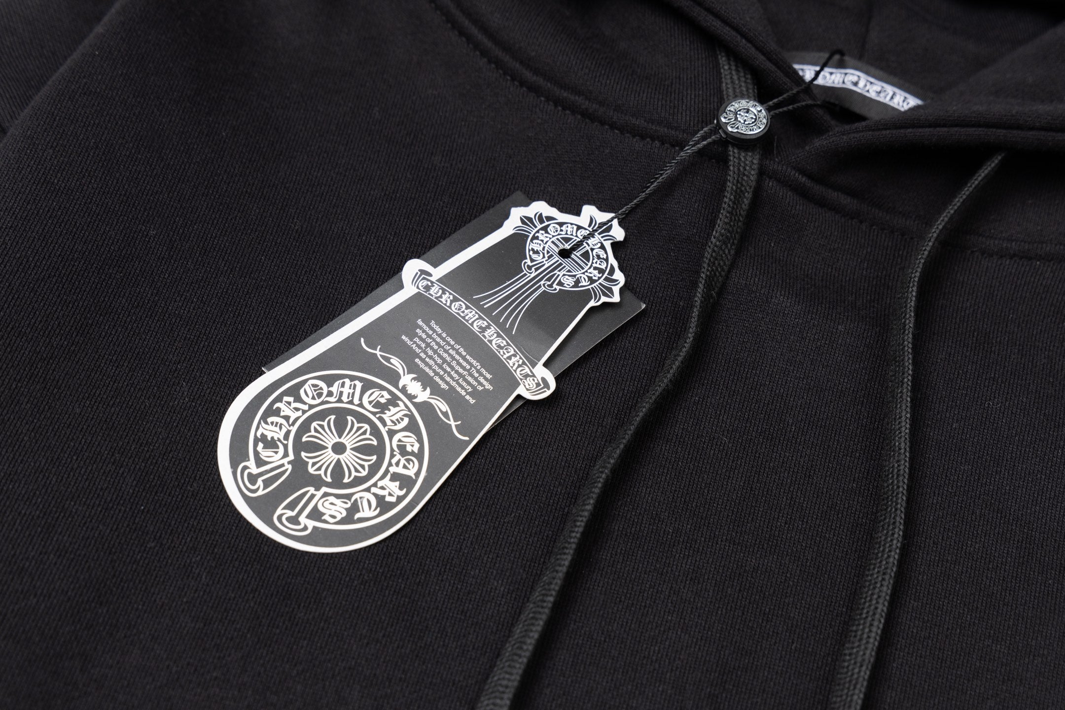 Black hoodie fabric close-up with woven neck label and drawstring top