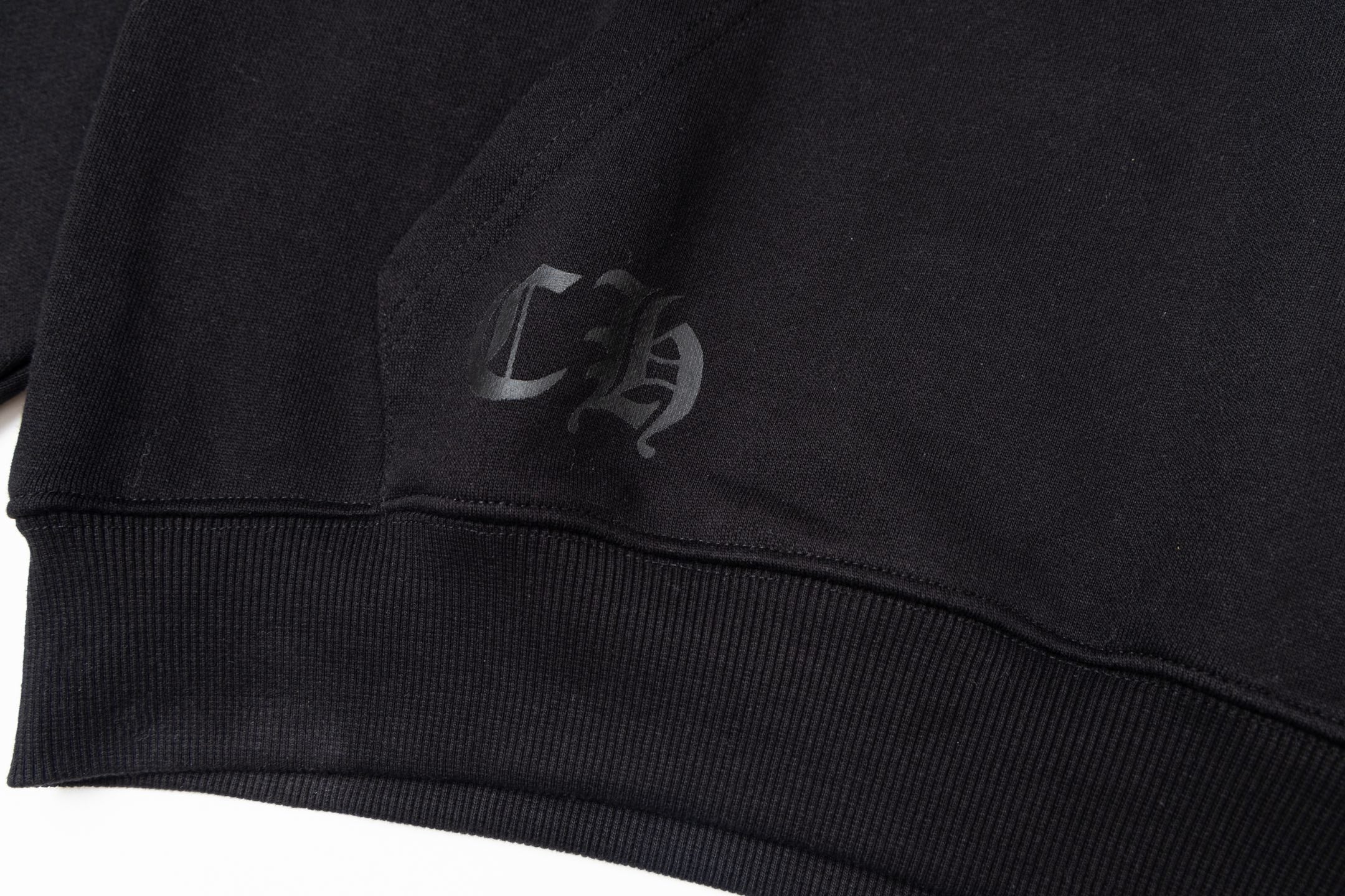Black long-sleeve hoodie with small chest logo on ribbed cuff