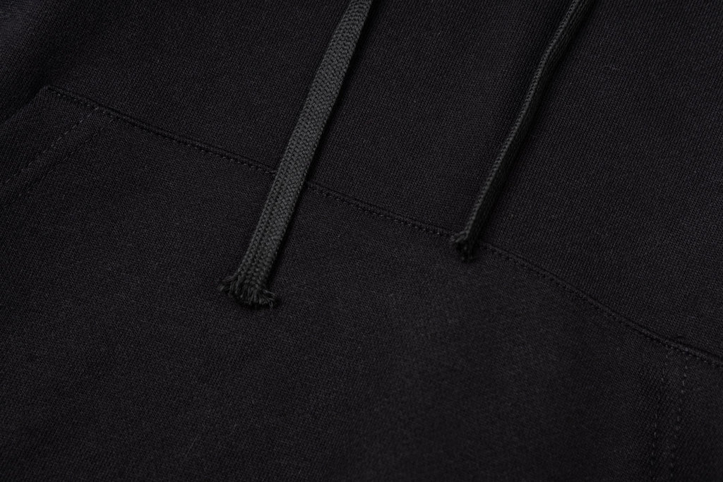 Black hoodie close-up showing kangaroo pocket opening and stitched hem