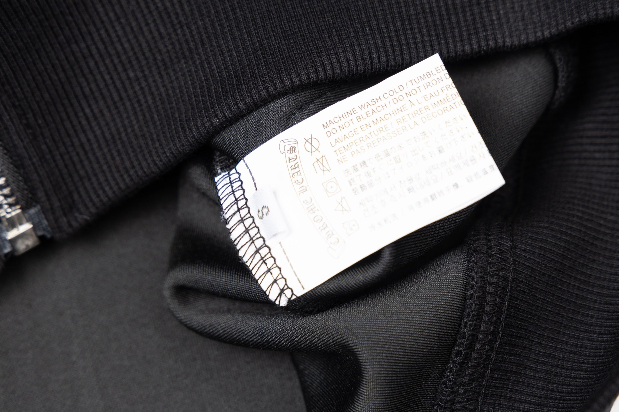 Black jacket neck label inside collar area with care and size info