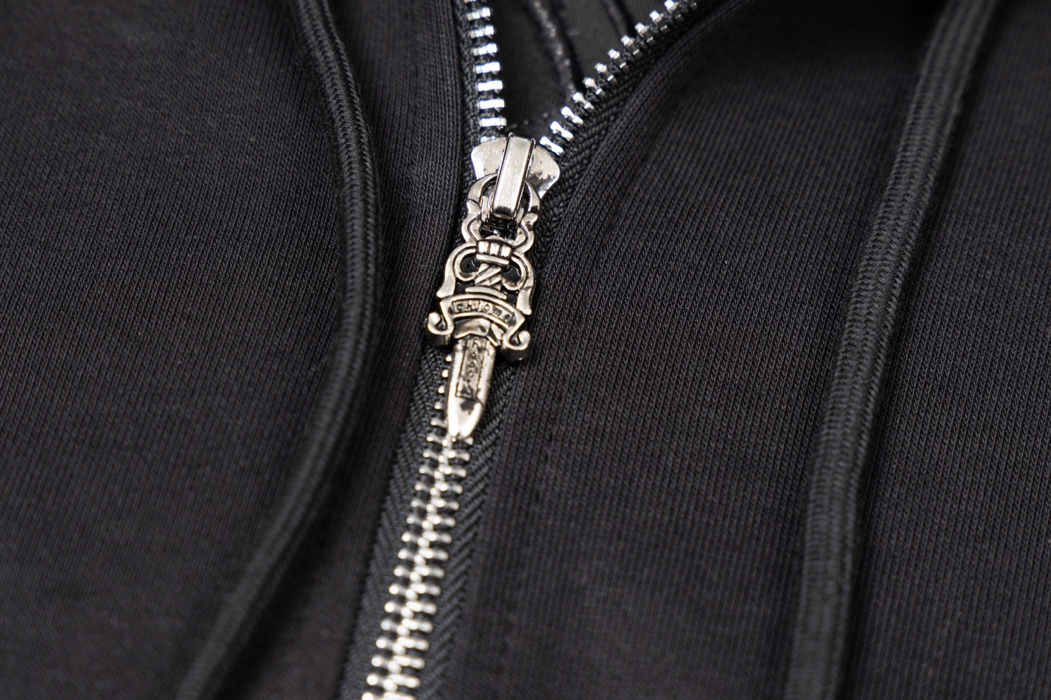 Silver zipper pull and teeth on black zip-up hoodie