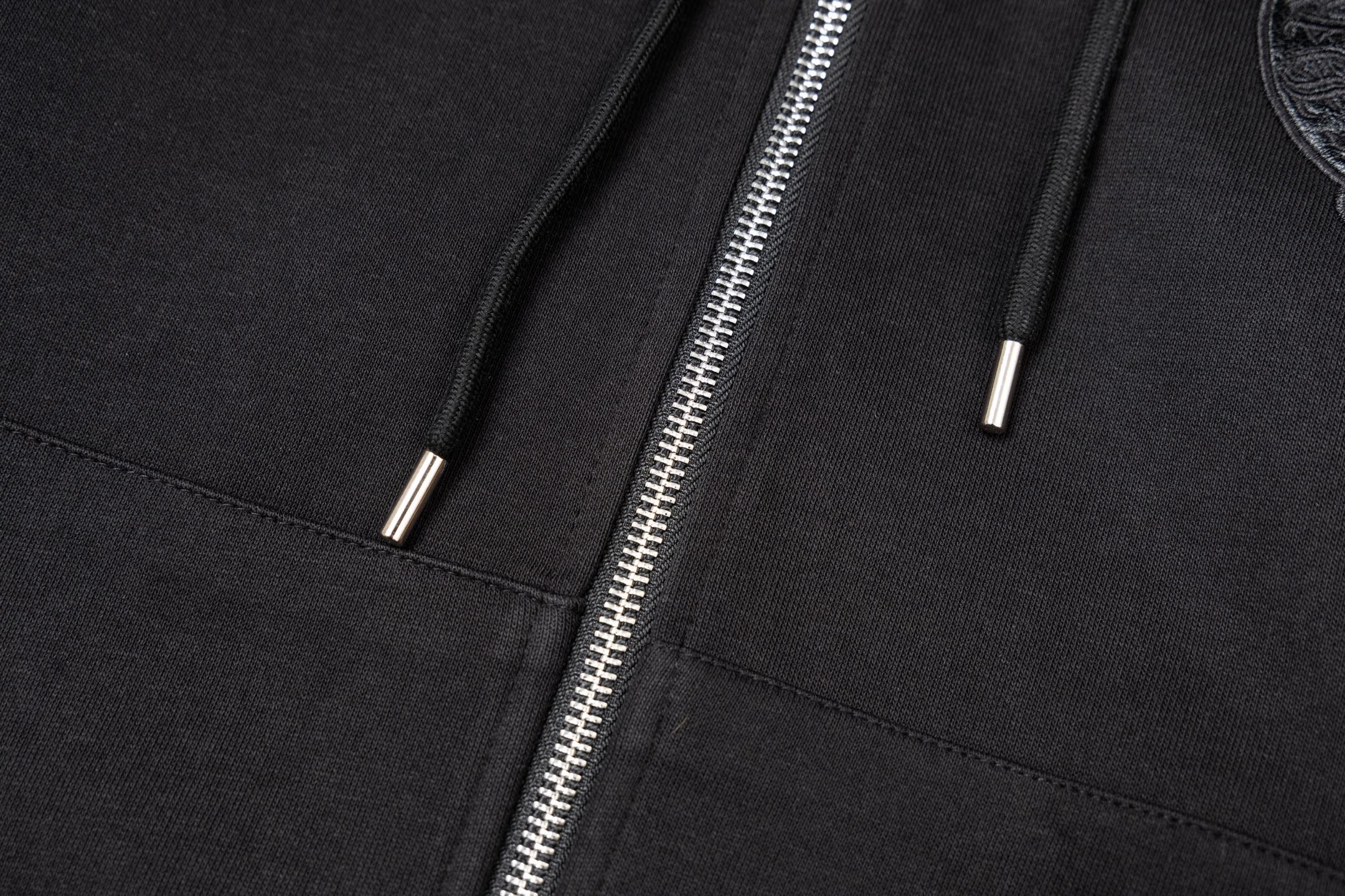 Black hoodie front close-up showing two drawstring tips and zipper seam