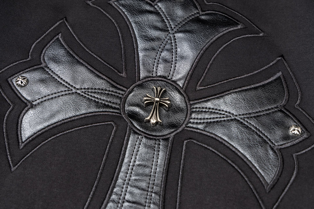 Black zip-up jacket with large chrome-style cross emblem and round metal button