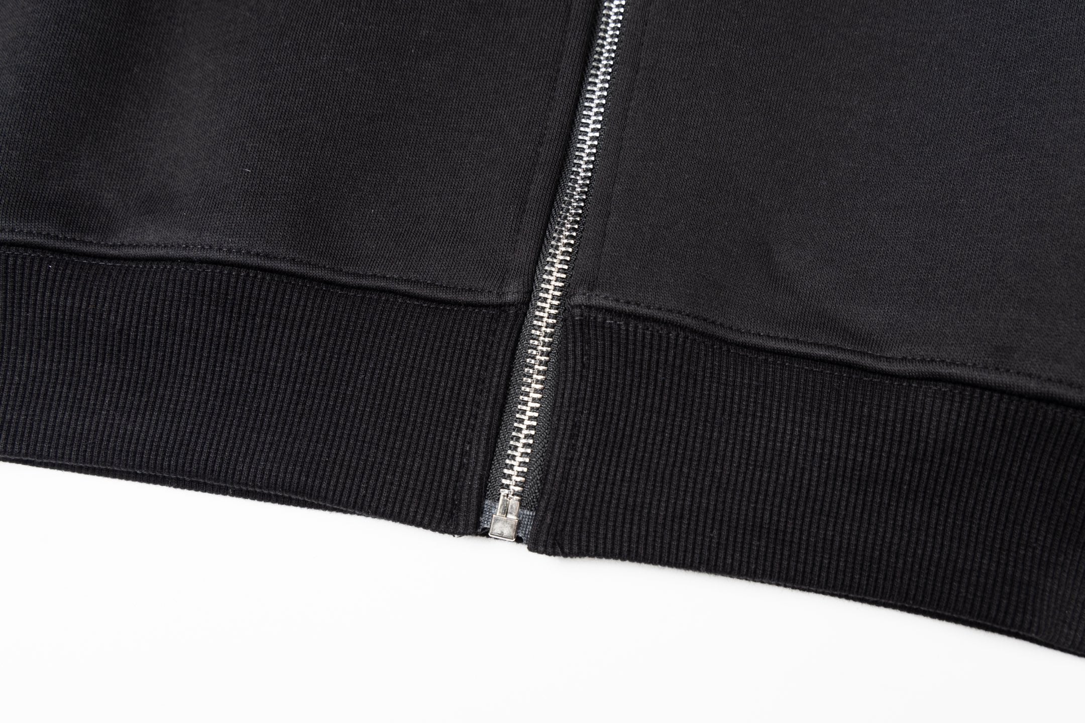 Black jacket hem with ribbed cuffs and metal zipper pull